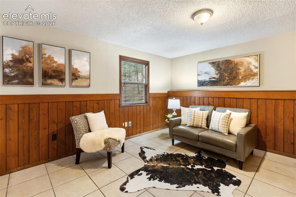 Image 23 of 41: Room featuring wood paneling, light-toned tile flooring, and a window with