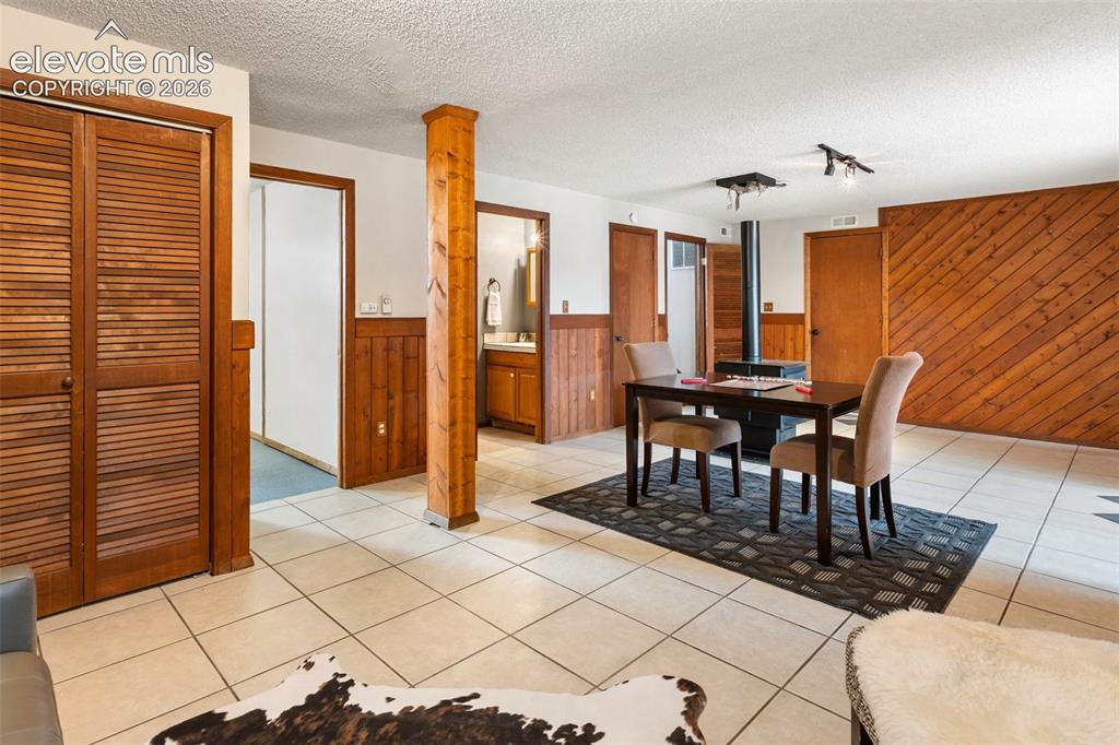 Image 27 of 41: Spacious room featuring light-toned square tile flooring, wood paneling, an