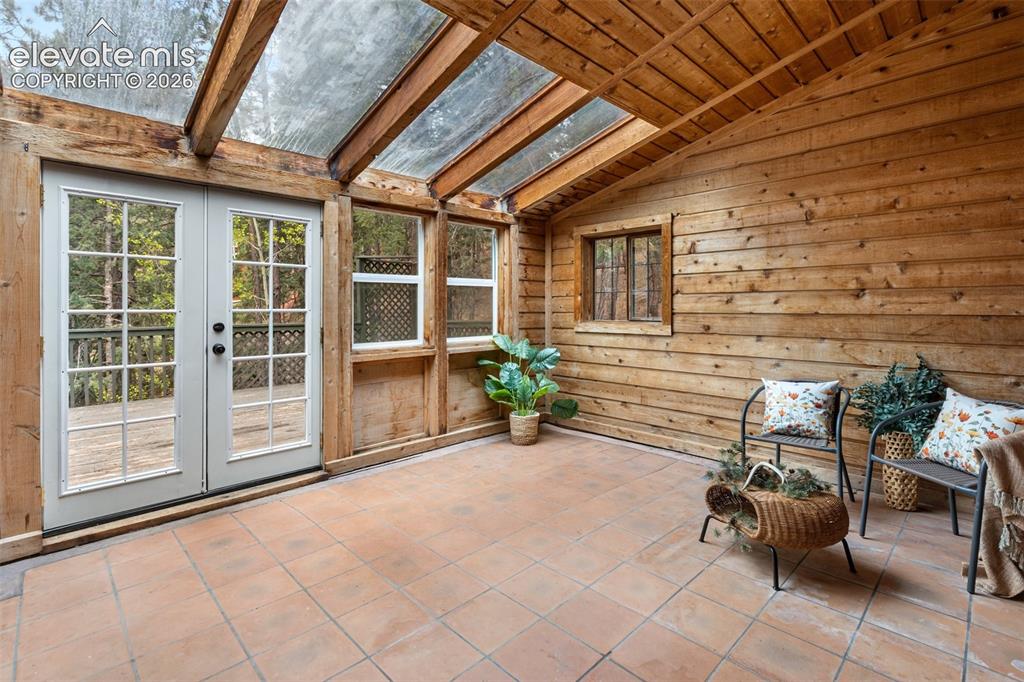 Image 28 of 41: Sunroom featuring a glass panel roof and wood-plank walls