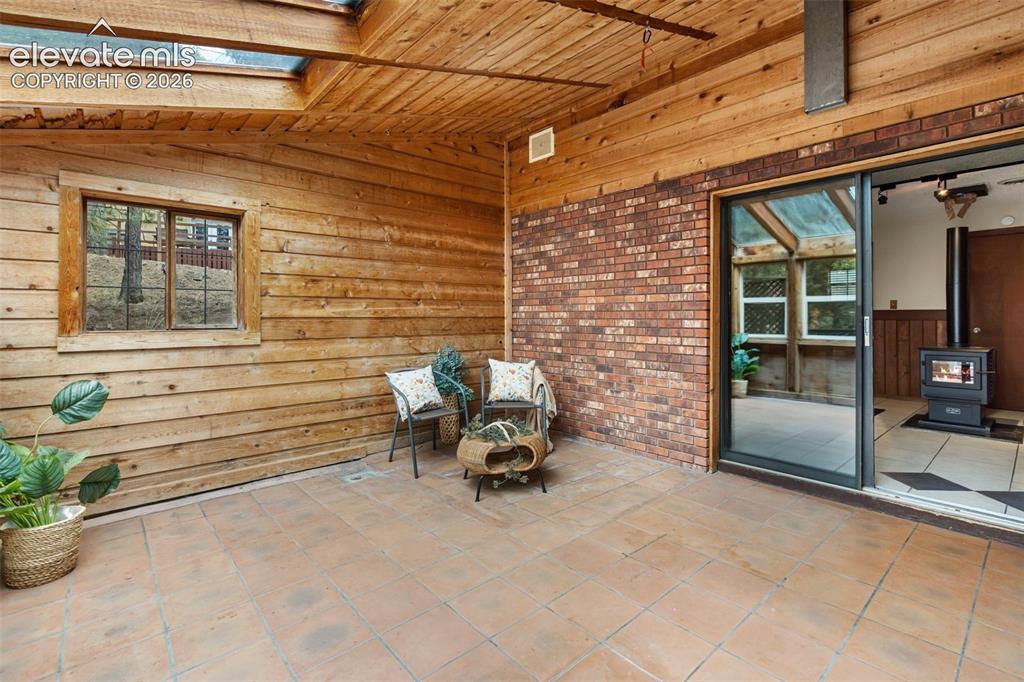 Image 29 of 41: Covered outdoor patio featuring tile flooring, exposed wood plank walls and