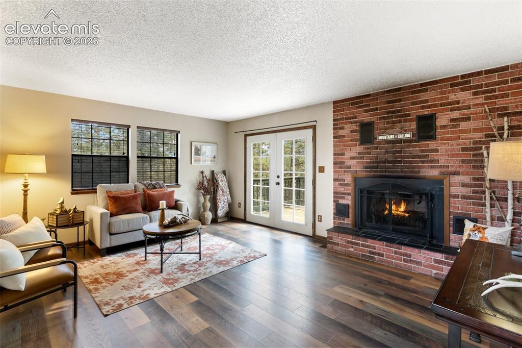 Image 3 of 41: Living area featuring a brick fireplace with a raised hearth, wood-finish f