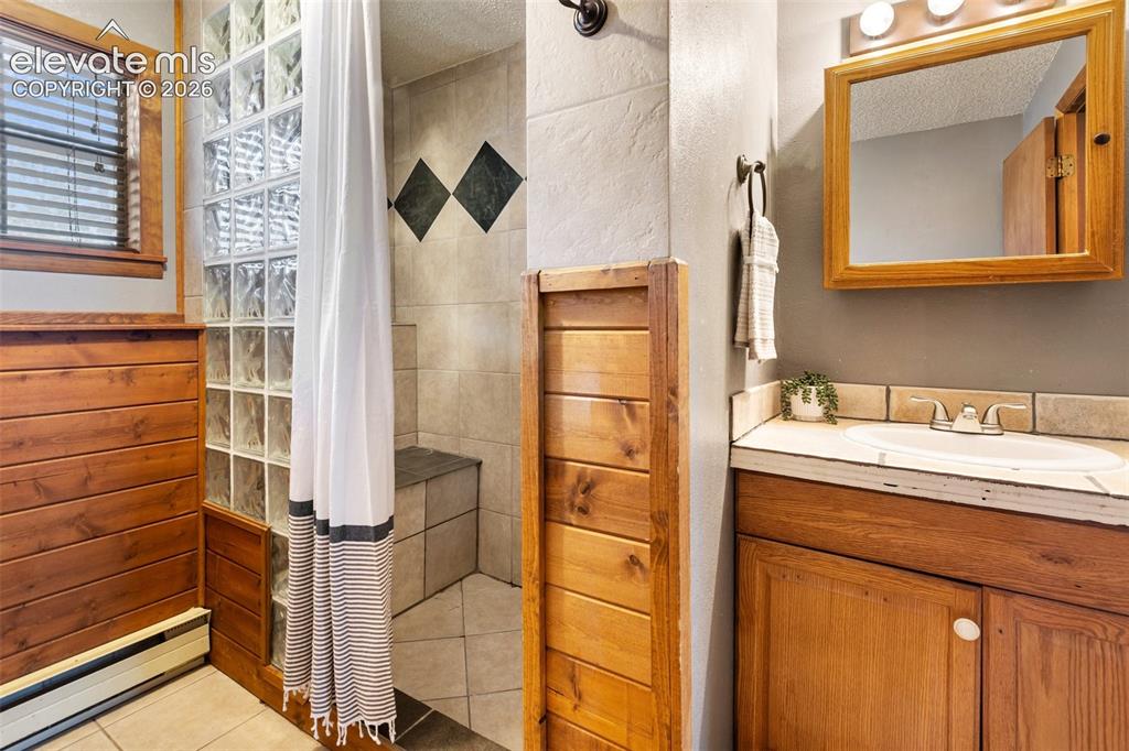 Image 31 of 41: Bathroom featuring a wood-panel accent wall and a glass block shower enclos