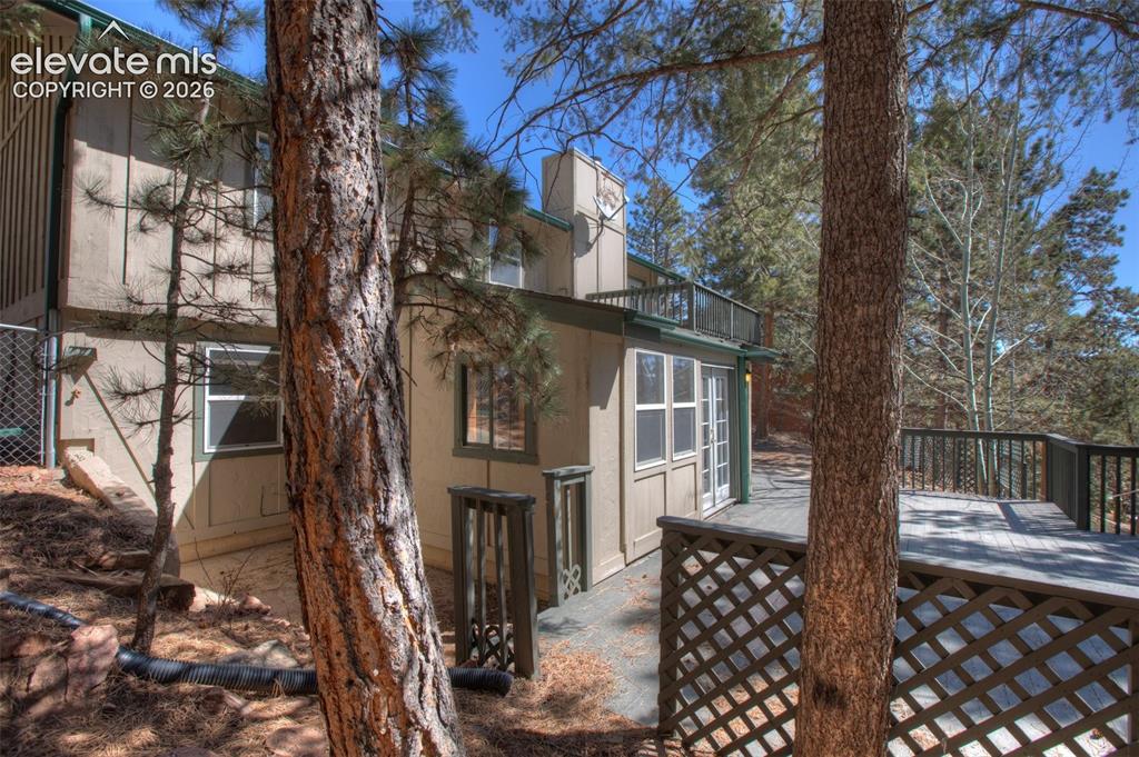 Image 32 of 41: Second Outdoor deck with lattice skirting and surrounding tree coverage. Ea