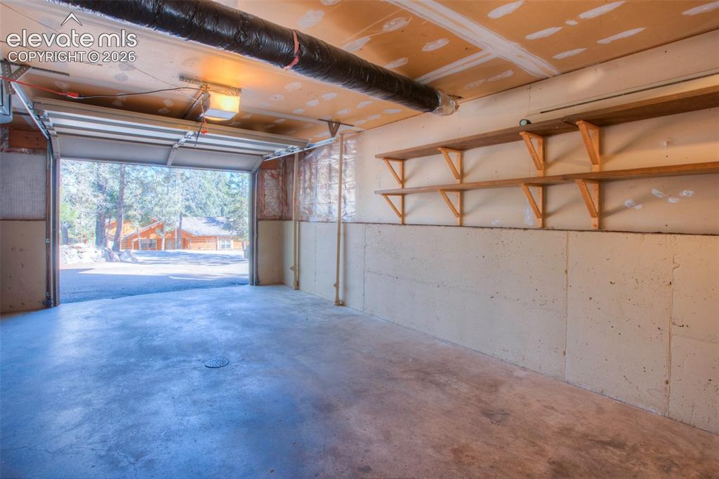 Image 35 of 41: Attached garage featuring a concrete floor, exposed ductwork, wall-mounted