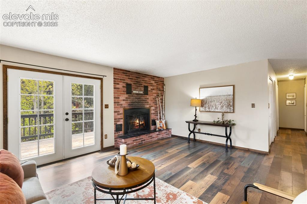 Image 4 of 41: Living area featuring a brick fireplace, wood-finish flooring, white double