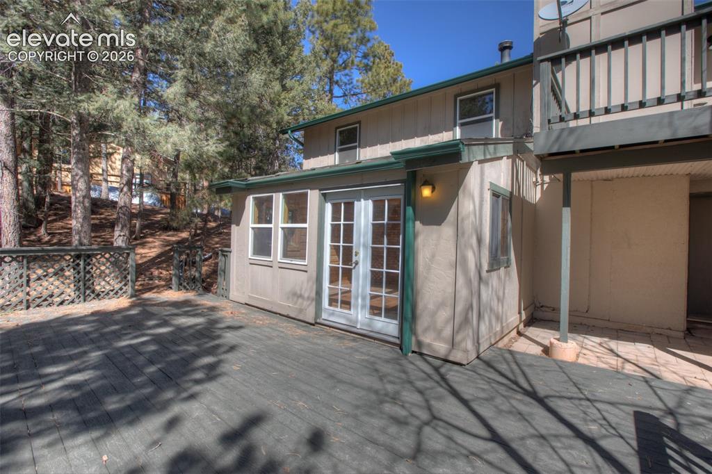 Image 40 of 41: Spacious exterior deck with lattice railing, double French doors, and ample