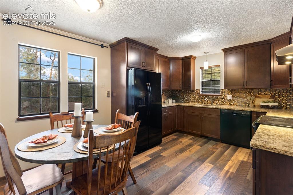 Image 7 of 41: Kitchen featuring wood-finish flooring, dark wood cabinetry, granite counte