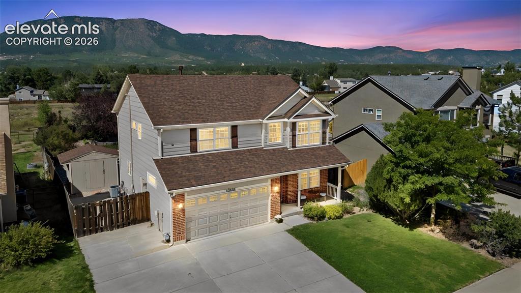 Caption: Two-story residence with a two-car garage, front porch, and a storage shed