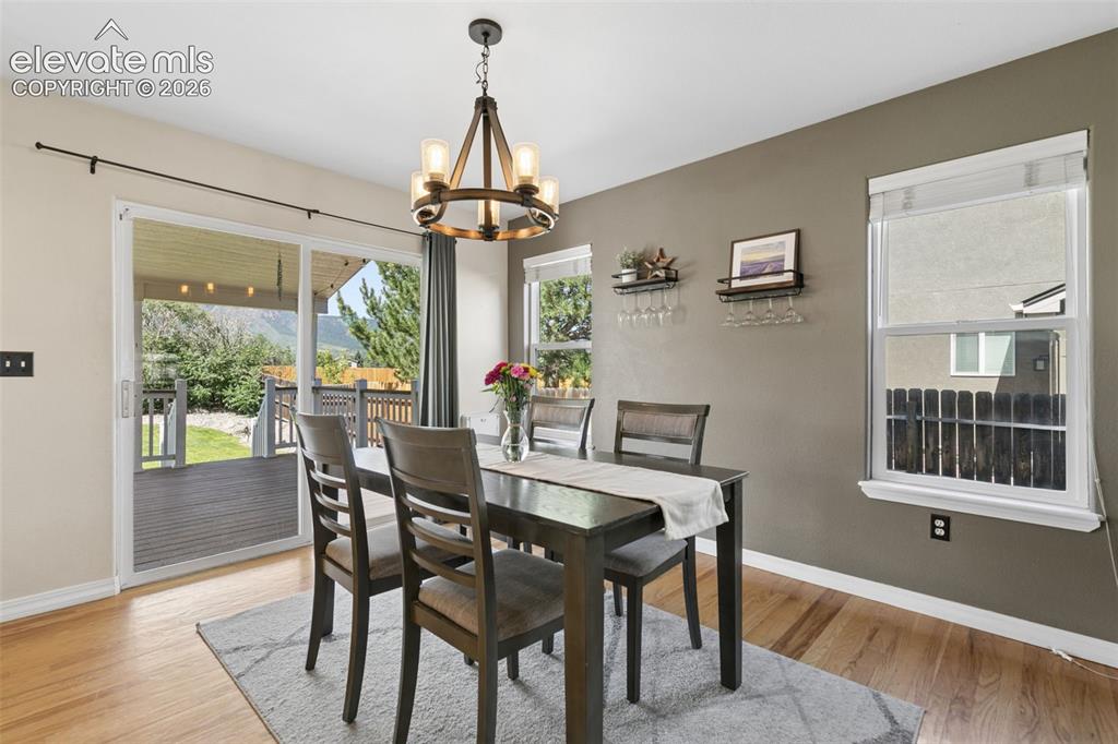 Image 13 of 48: Hardwood flooring, sliding glass door, outdoor deck, chandelier lighting, a
