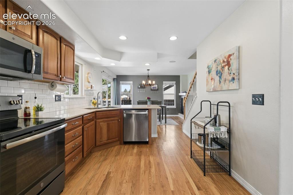 Image 15 of 48: Kitchen featuring wood-finish flooring, stainless steel appliances, and whi