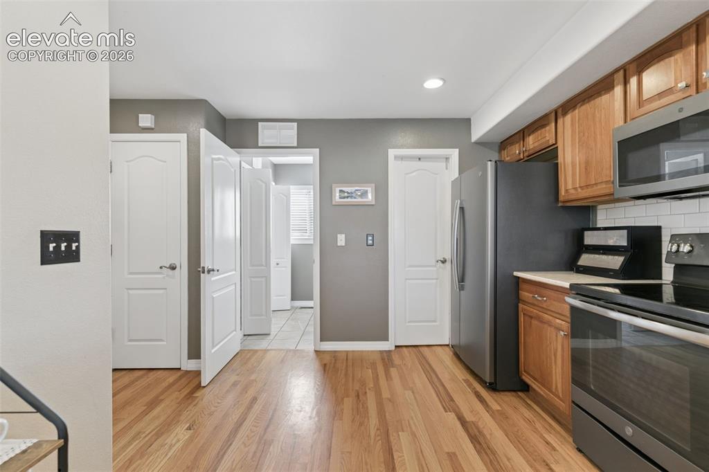 Image 16 of 48: Wood-finish flooring, recessed lighting, and white subway tile backsplash