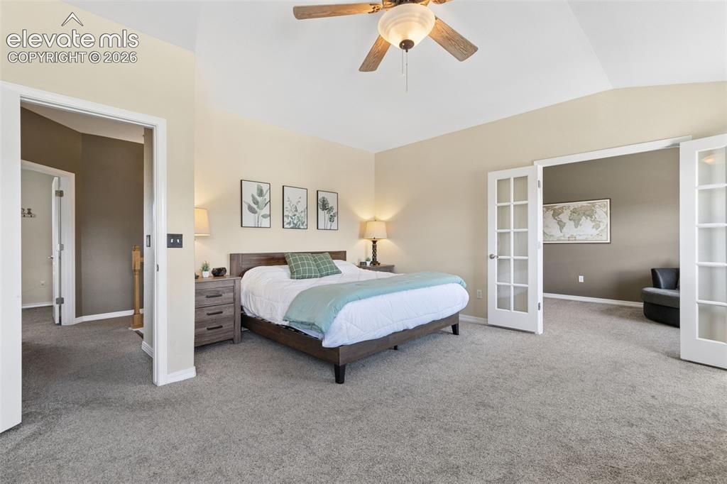 Image 19 of 48: Vaulted ceiling with a ceiling fan, plush gray carpeting, and double French