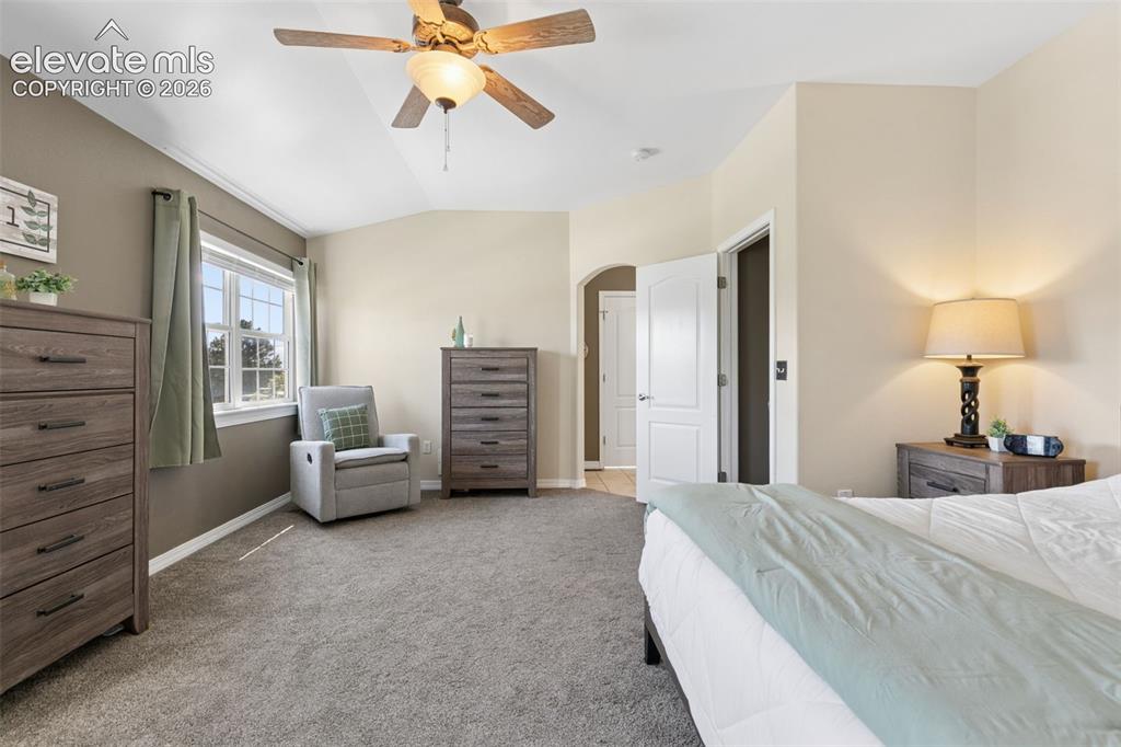 Image 21 of 48: Vaulted ceiling with a ceiling fan, carpeted flooring, and an arched doorwa