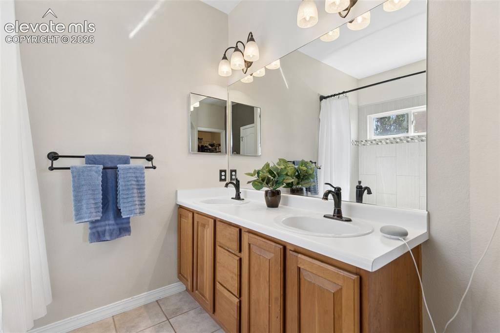 Image 24 of 48: Dual vanity with white countertop, wood-finish cabinetry, and matte black f