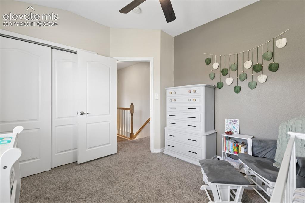 Image 27 of 48: Sliding closet doors, ceiling fan, carpeted flooring, and a neutral color p