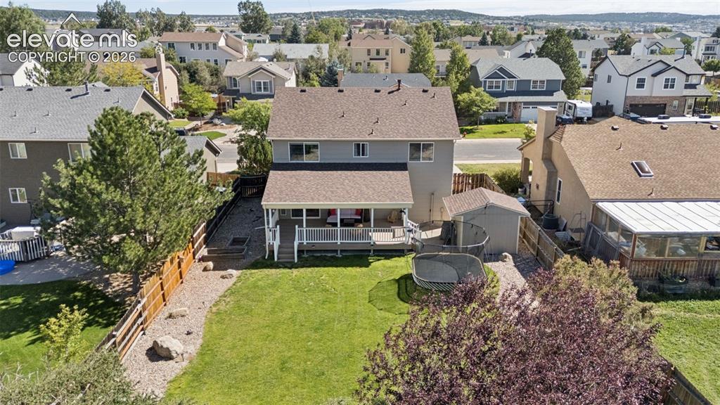 Image 3 of 48: Expansive backyard featuring a manicured lawn, established trees, and a cov