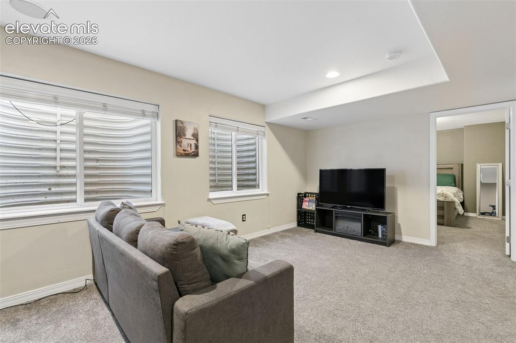 Image 32 of 48: Recessed lighting, wall-to-wall carpeting, and a built-in media console wit
