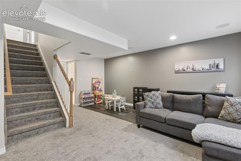 Image 34 of 48: Carpeted staircase with wood railing, recessed lighting, and wood-finish fl