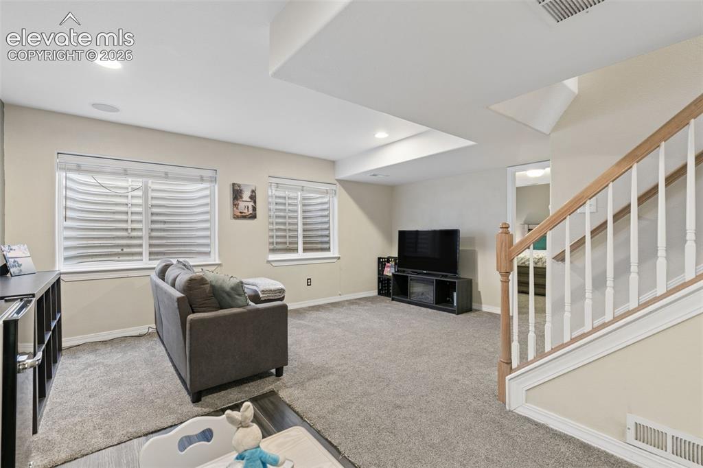 Image 35 of 48: Carpeted flooring, recessed lighting, and a white and wood-finish staircase