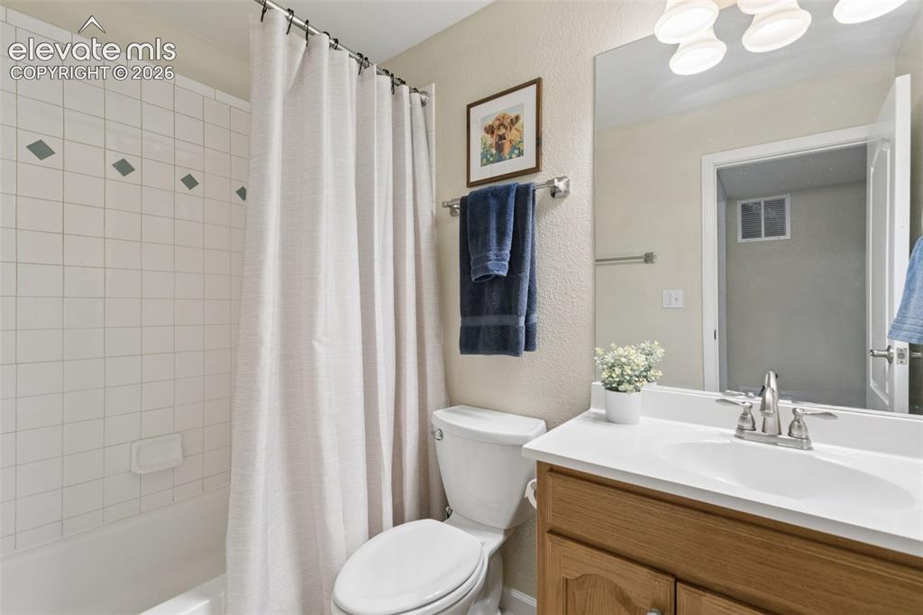 Image 37 of 48: Bathroom featuring a built-in tub with white tile surround, a single vanity