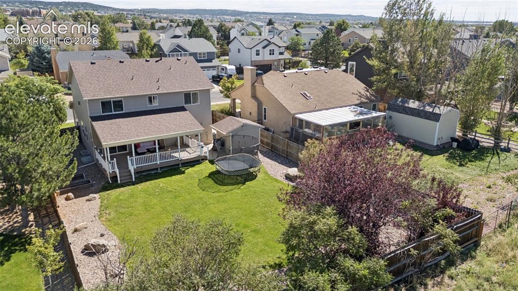Image 4 of 48: Expansive backyard with a manicured lawn, covered deck, and established tre