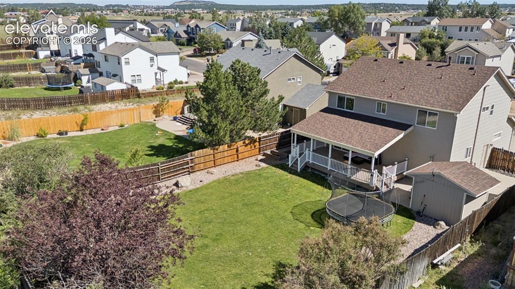 Image 43 of 48: Expansive backyard with a covered deck, separate outdoor shed, and a privac