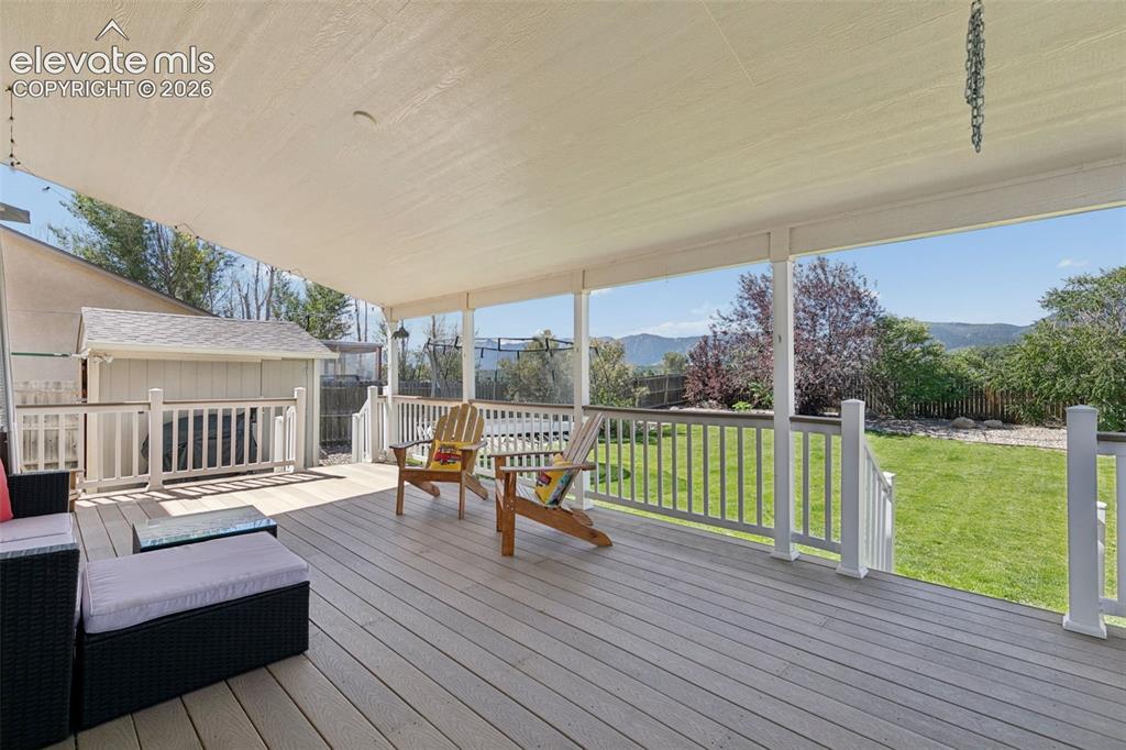 Image 5 of 48: Expansive outdoor deck with a shade canopy, white railing, and a storage sh