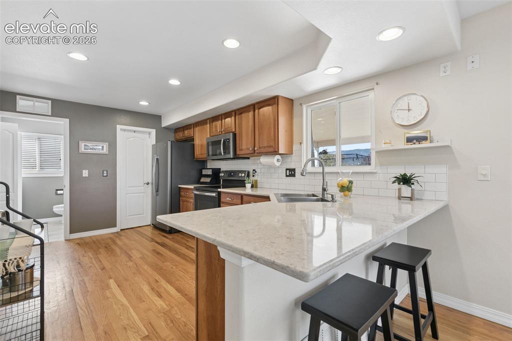 Image 9 of 48: Kitchen with wood-finish flooring, recessed lighting, and a breakfast bar w