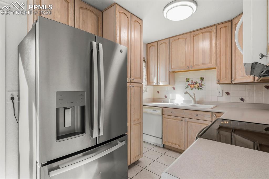 Image 11 of 49: Kitchen featuring light brown cabinetry, white appliances, light countertop
