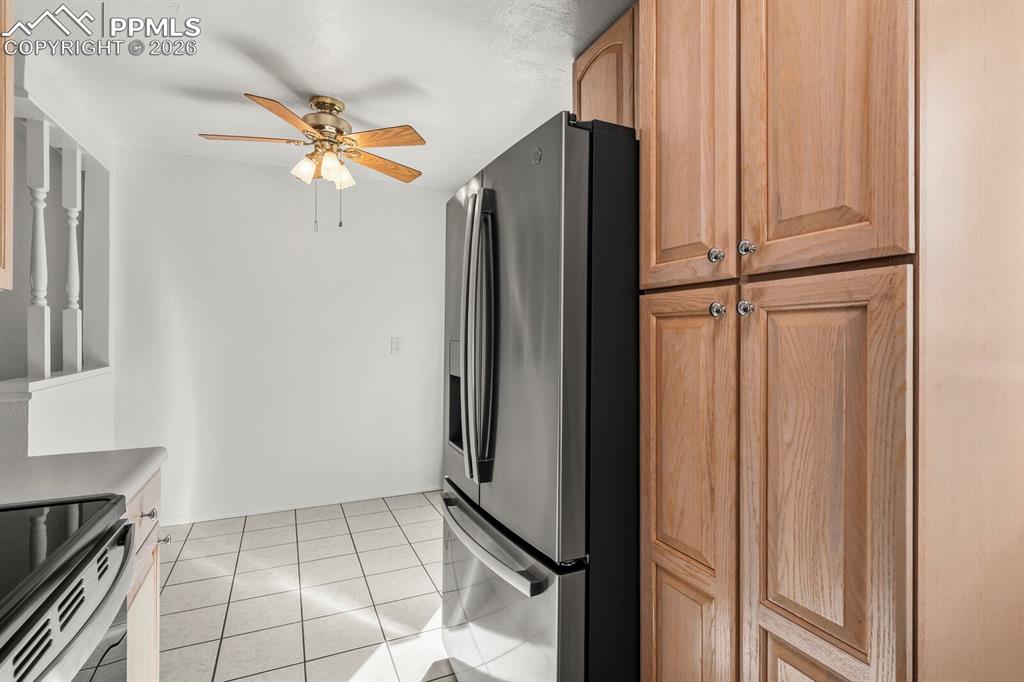 Image 13 of 49: Kitchen with stainless steel refrigerator with ice dispenser, light tile pa