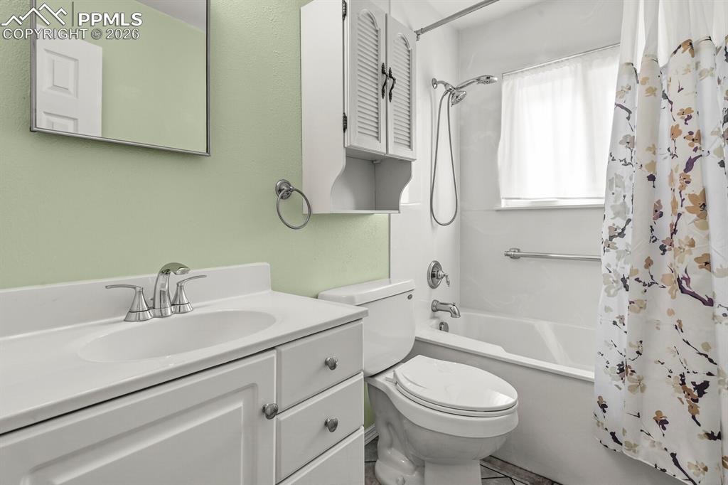 Image 19 of 49: Bathroom featuring shower / bath combination with curtain and vanity