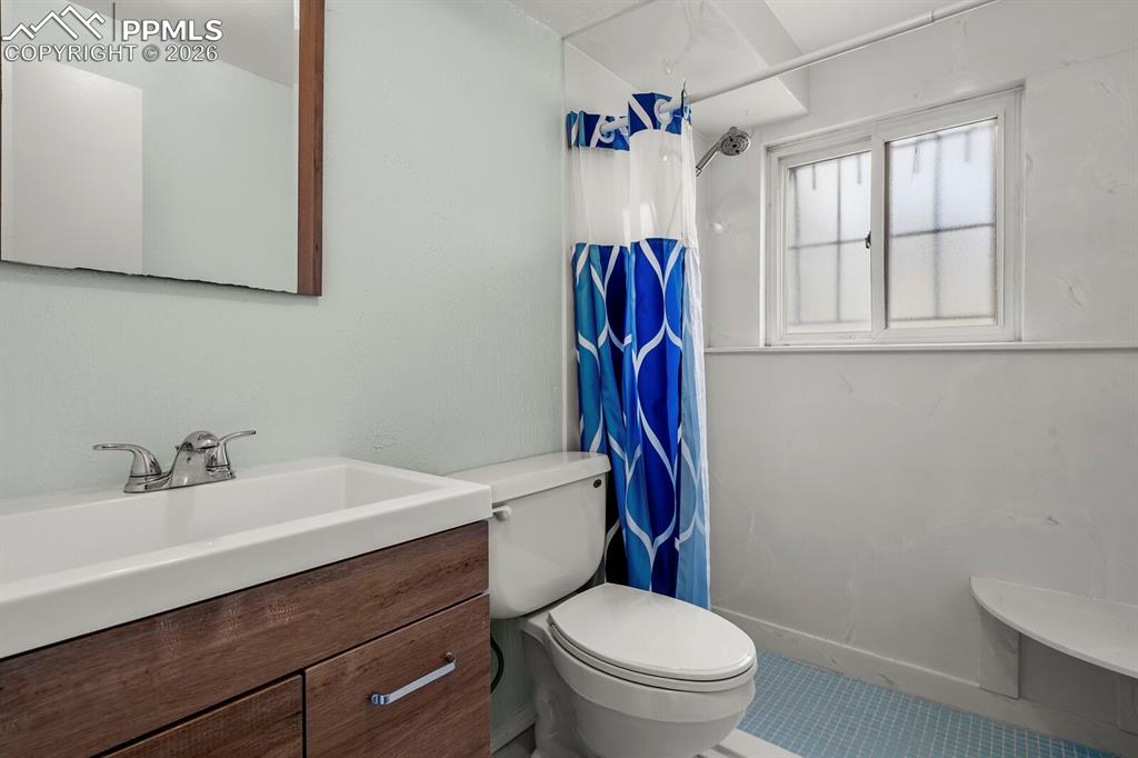 Image 27 of 49: Bathroom featuring a shower with shower curtain and vanity