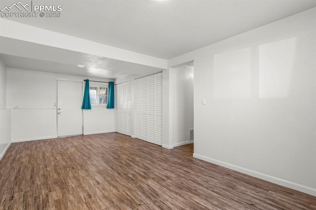 Image 32 of 49: Spare room with dark wood-type flooring and baseboards