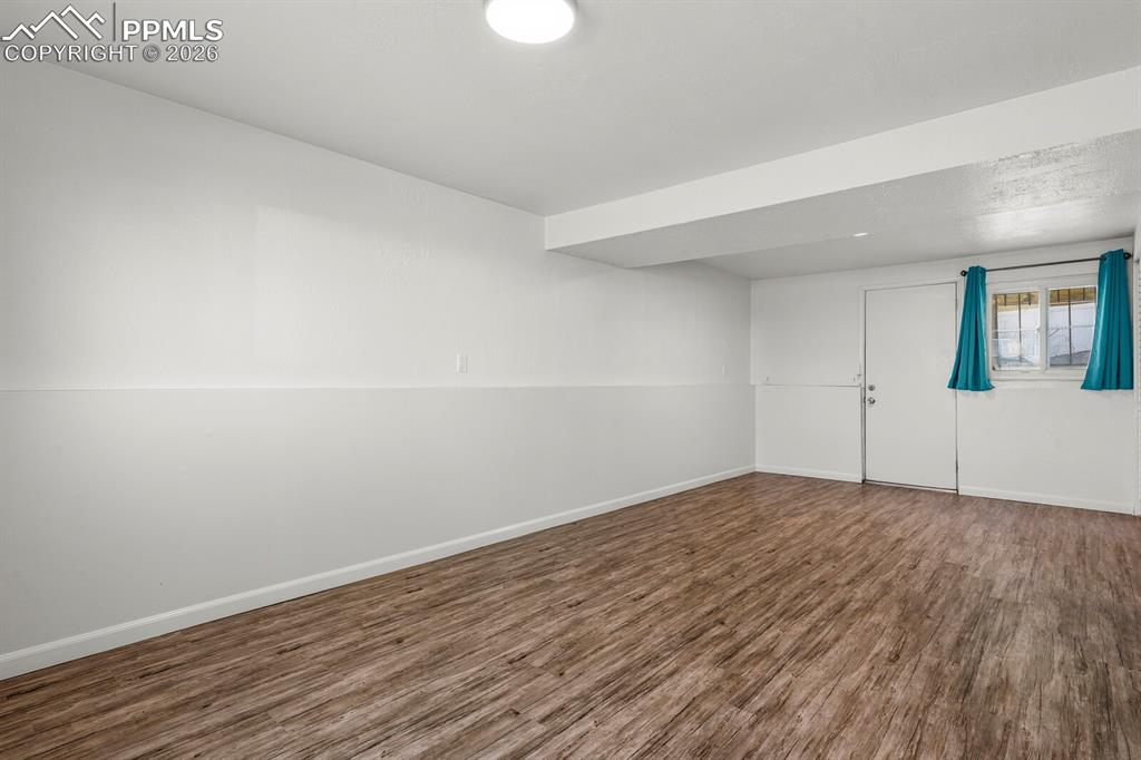 Image 33 of 49: Basement with dark wood finished floors and baseboards