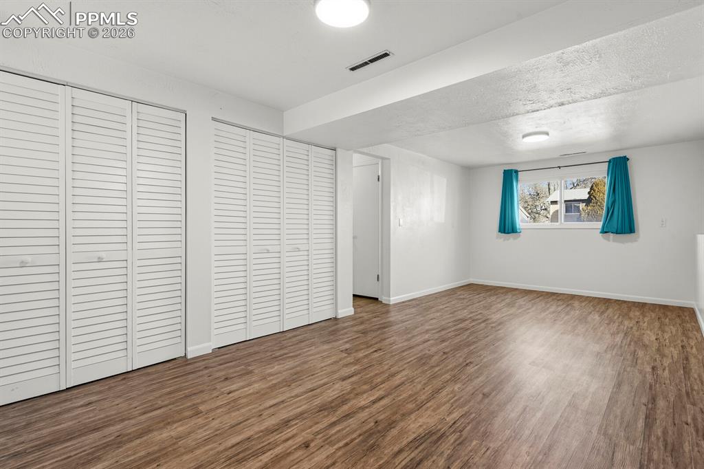 Image 34 of 49: Unfurnished bedroom featuring dark wood-style floors, two closets, and a te