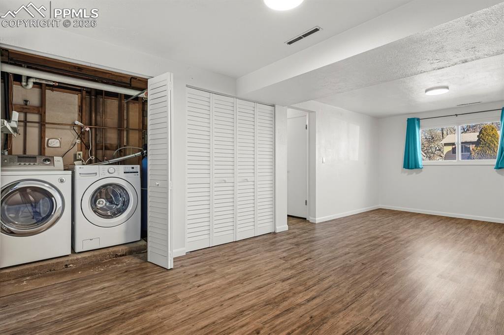 Image 35 of 49: Laundry area with dark wood-type flooring, washer and clothes dryer, and a 
