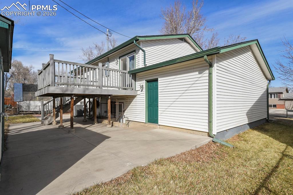 Image 39 of 49: View of side of home featuring a wooden deck, stairs, a patio, and a yard