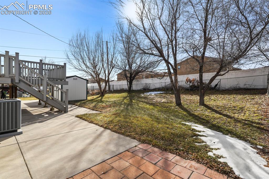 Image 41 of 49: Fenced backyard with stairway, a patio area, a storage shed, and a wooden d