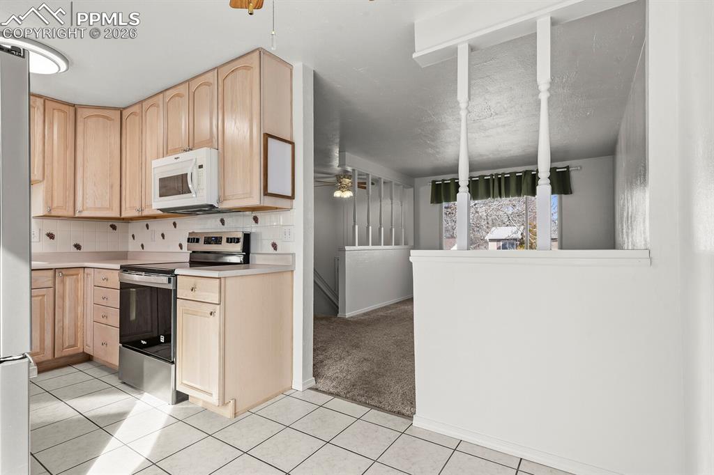 Image 9 of 49: Kitchen featuring light brown cabinets, stainless steel electric range, lig