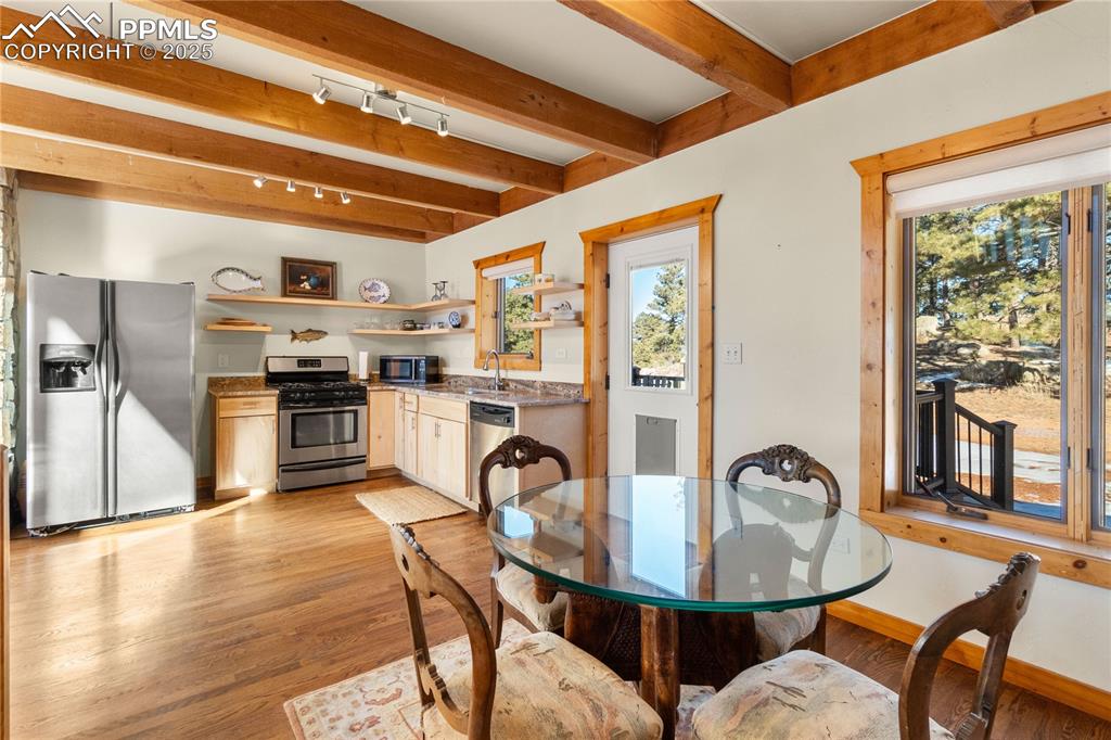 Image 14 of 46: An alternate view of the dining area and kitchen with beautiful beams and c