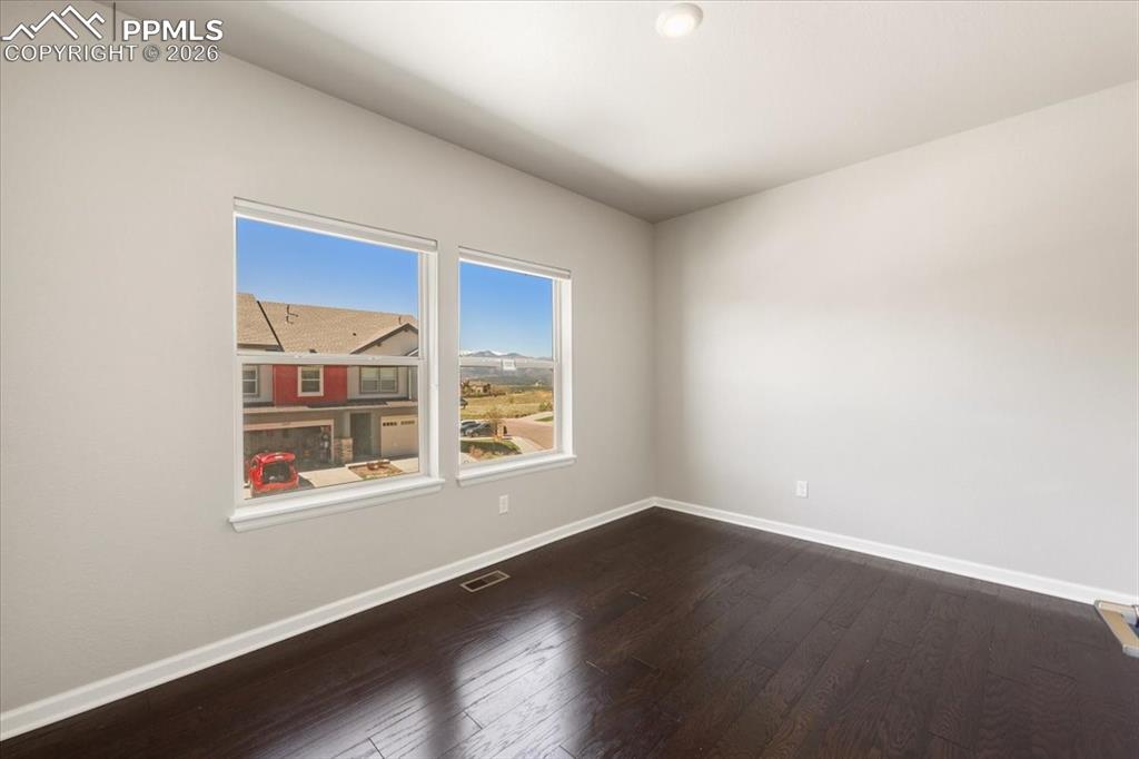 Image 11 of 19: Spare room with visible vents, baseboards, and dark wood finished floors