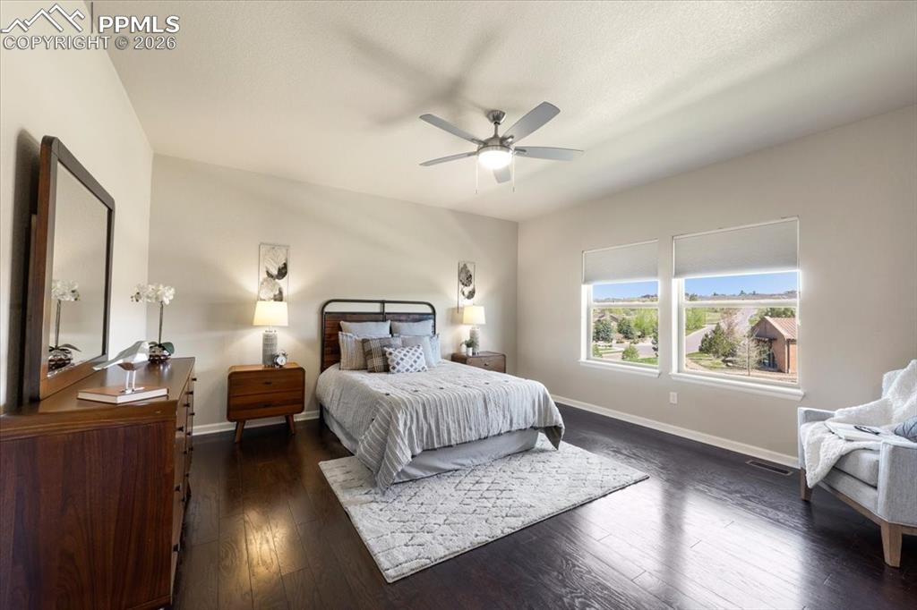 Image 14 of 19: Bedroom featuring a ceiling fan, baseboards, and dark wood-style floors