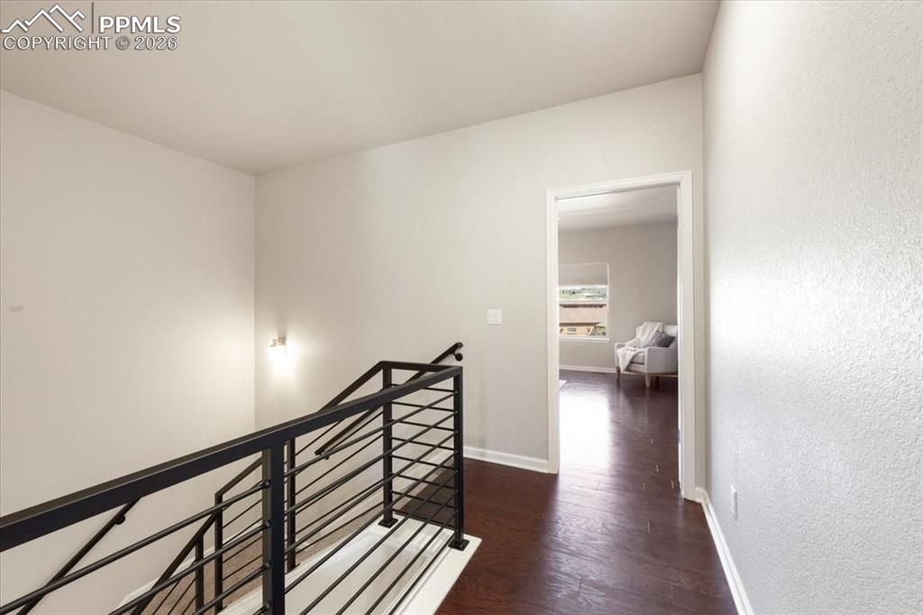 Image 15 of 19: Corridor with a textured wall, baseboards, an upstairs landing, and wood fi