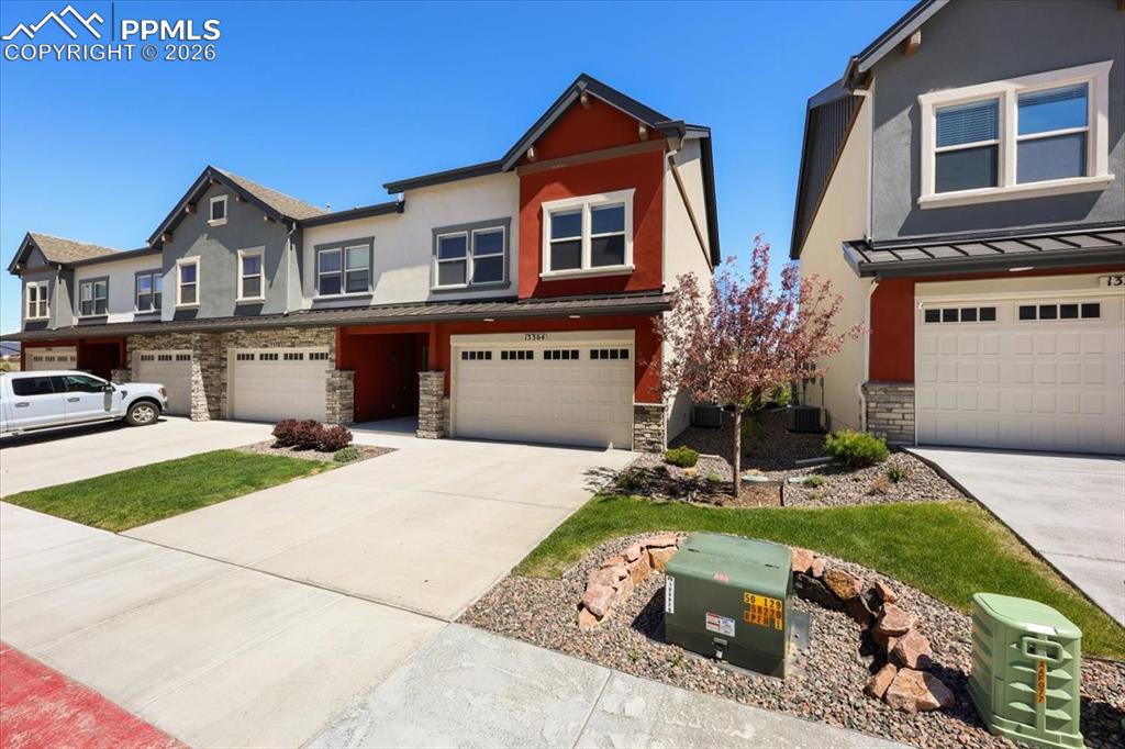 Image 2 of 19: View of front facade featuring stucco siding, driveway, stone siding, an at