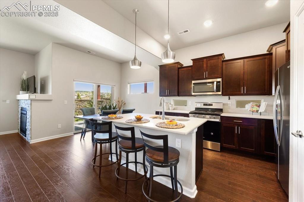 Image 3 of 19: Kitchen featuring a breakfast bar, light countertops, dark wood finished fl