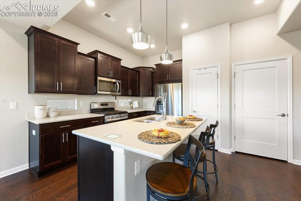 Image 6 of 19: Kitchen featuring dark wood-type flooring, baseboards, a sink, and applianc