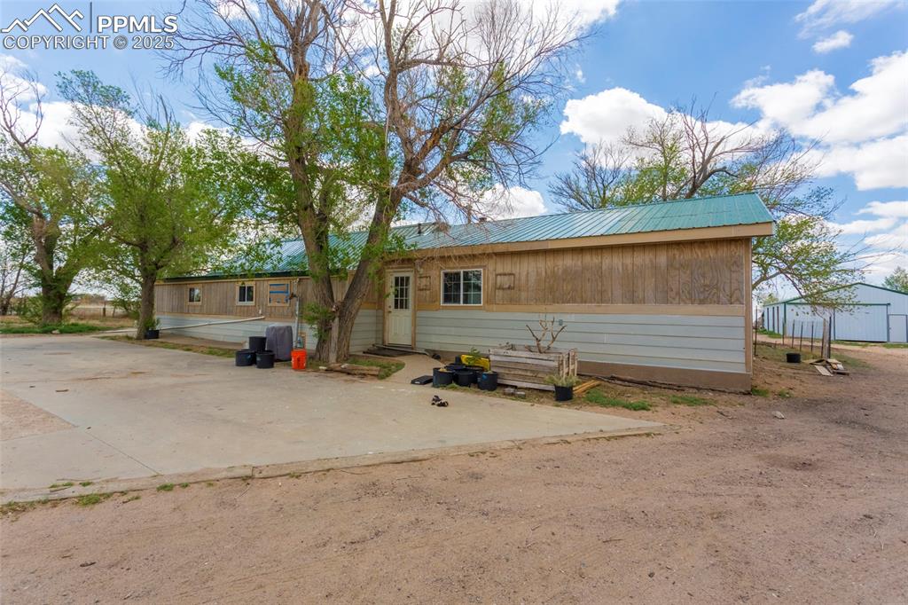 Image 2 of 26: View of front of property with driveway, metal roof, and a patio