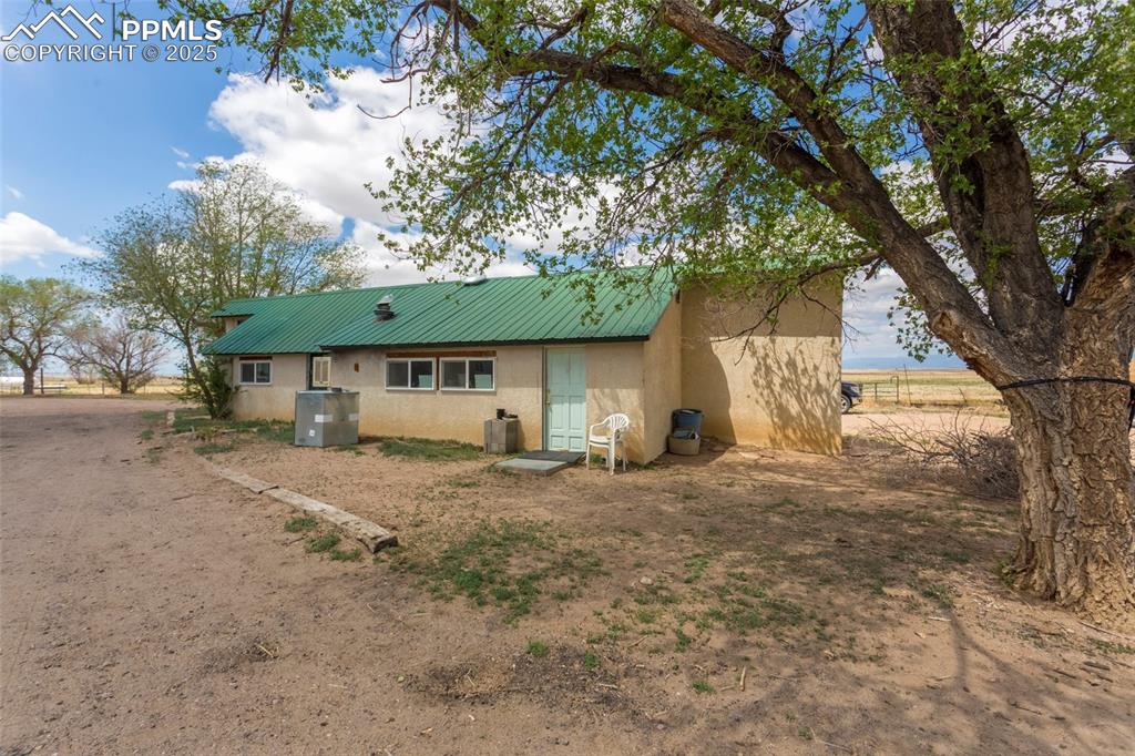 Image 5 of 26: Back of property featuring metal roof and stucco siding