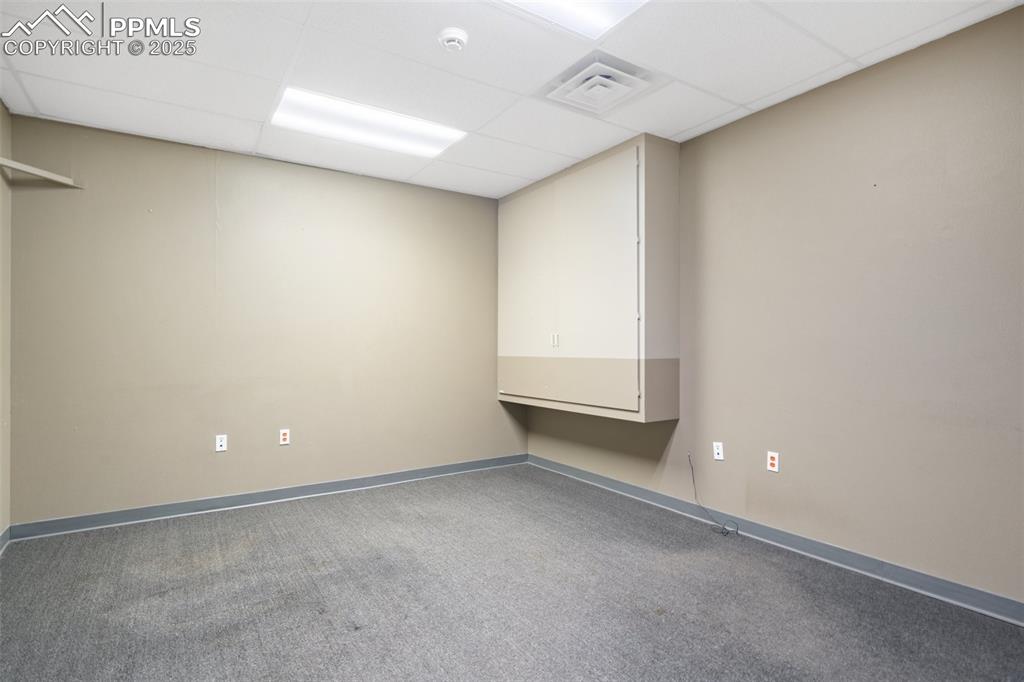 Image 15 of 26: Carpeted spare room with a paneled ceiling and a smoke detector