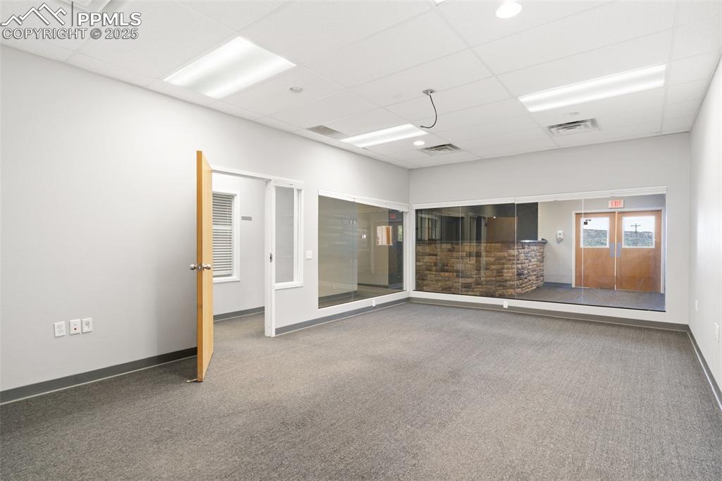 Image 16 of 26: Unfurnished room featuring a drop ceiling and carpet